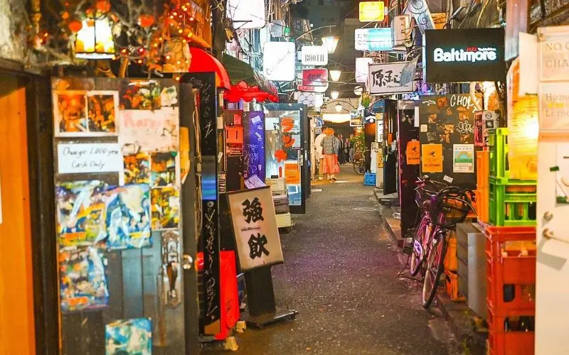Narrow alley of Golden Gai lined with colorful bars and signs.