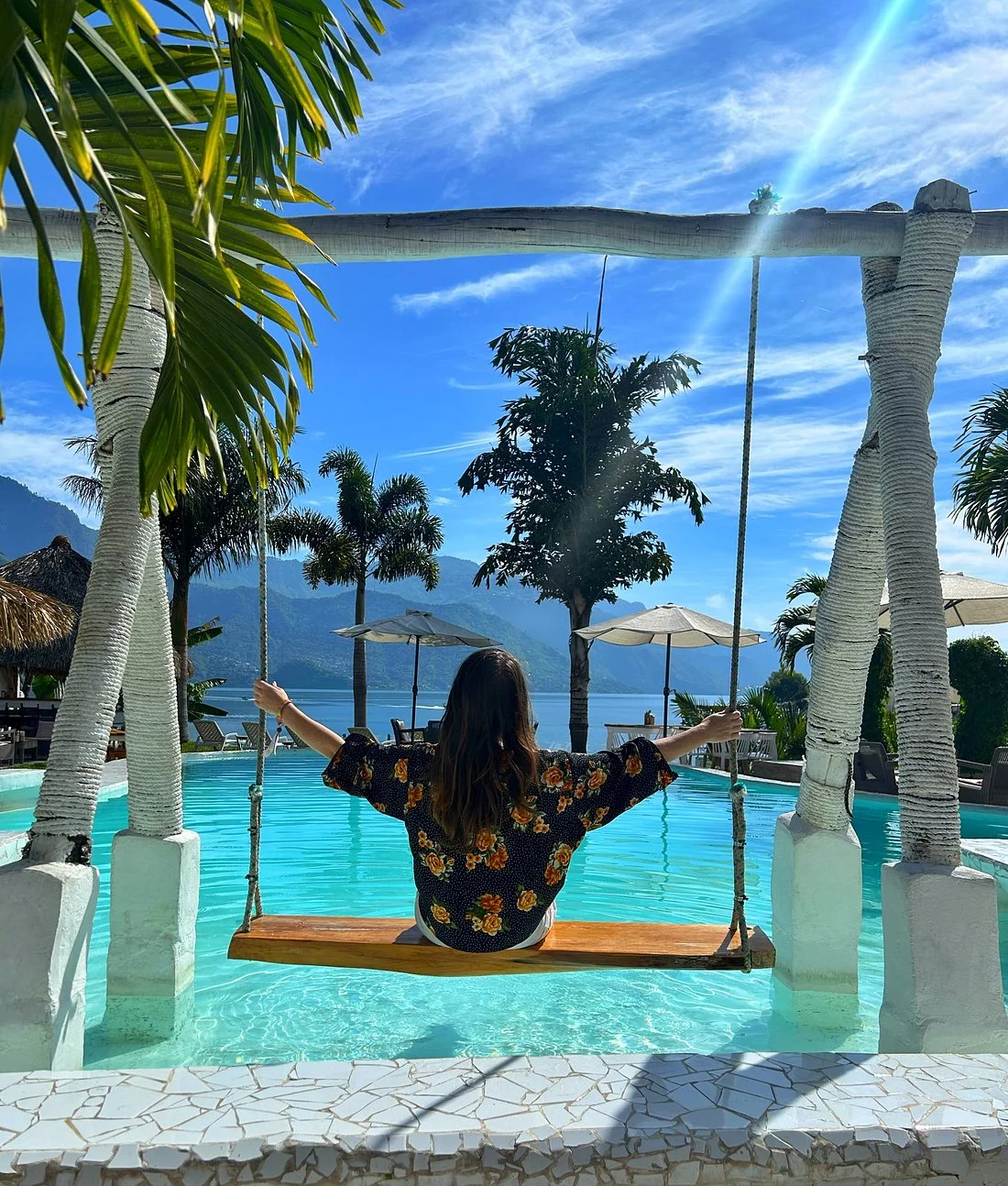 Woman relaxing on pool swing at Sababa Resort with Lake Atitlan volcano views, one of the best things to do in San Pedro La Laguna Guatemala