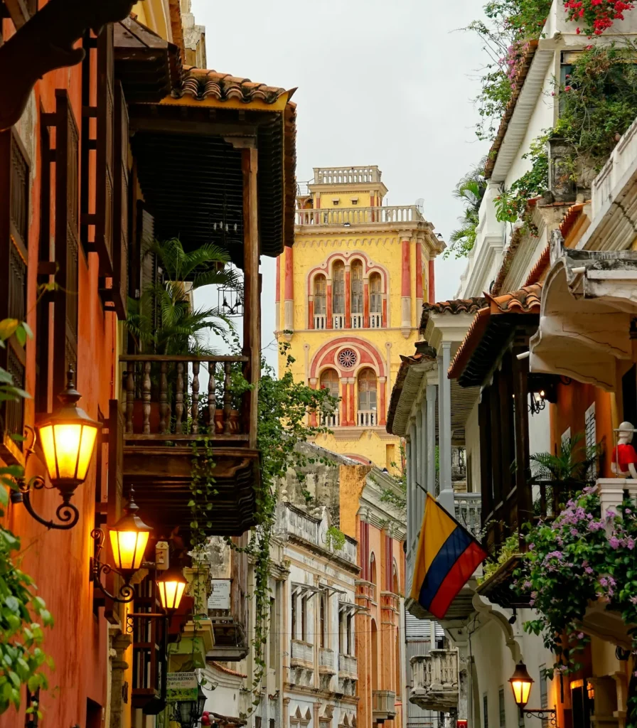 The yellow Cartagena Cathedral tower framed by narrow colonial streets and a Colombian flag