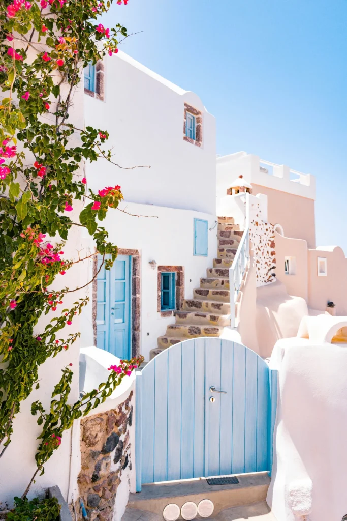 Whitewashed buildings with blue doors and pink flowers in Santorini