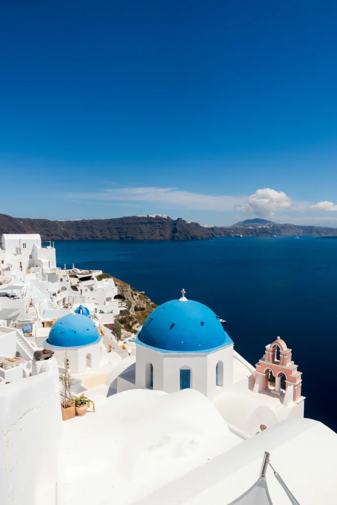 Blue dome churches and white houses overlooking the sea in Oia, Santorini