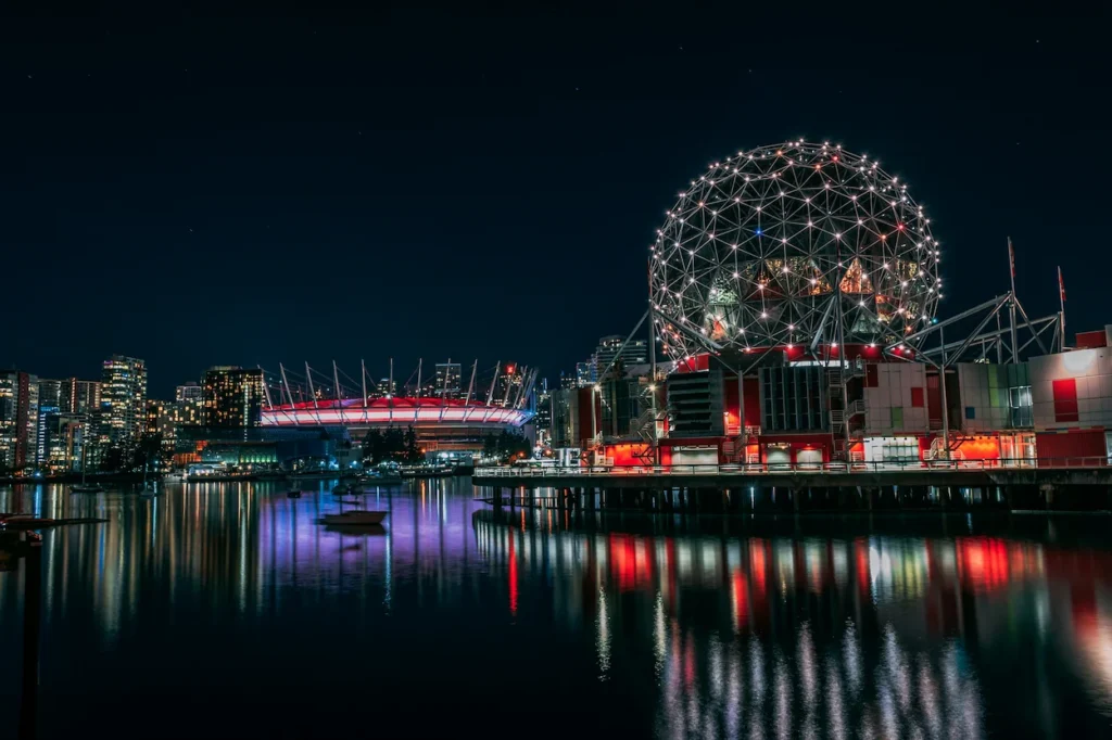 Illuminated geodesic dome of Science World and the glowing roof of BC Place stadium at night