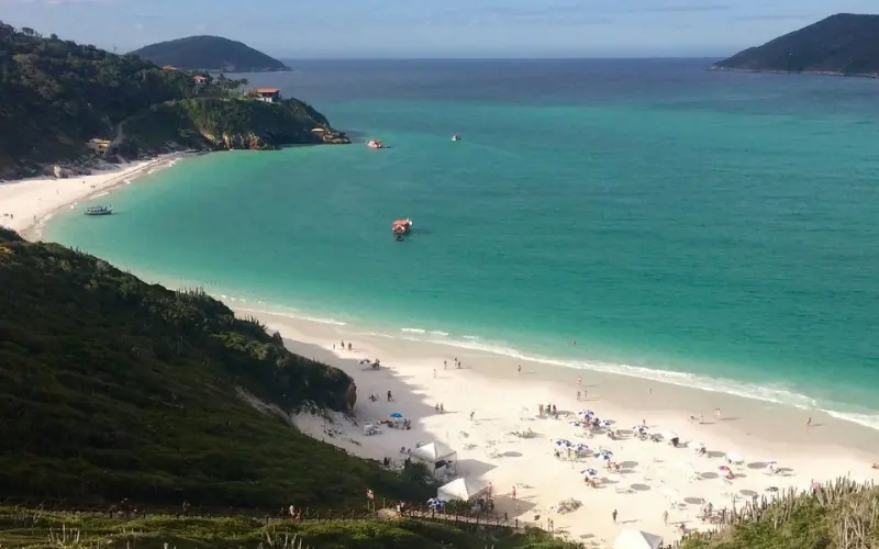 Brazil shows a white sandy beach with turquoise water and green hills.