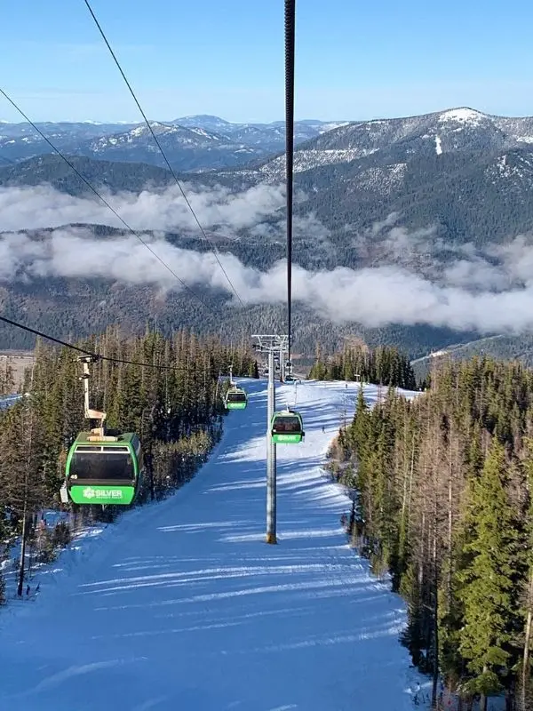 Ski gondolas travel over snowy mountains and trees at Silver Mountain Resort.