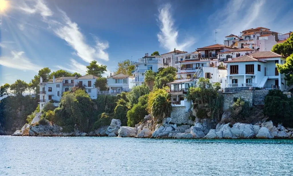White houses perched on a cliff by the sea in Skiathos, Greece.