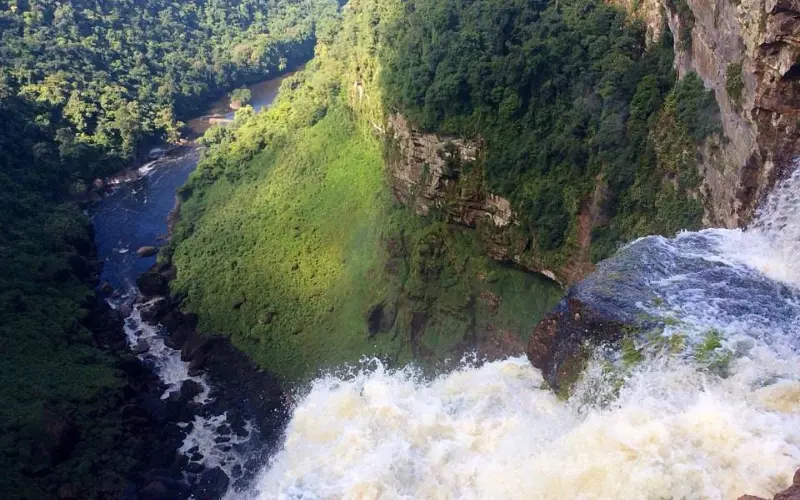Guyana features a tall waterfall dropping into a green valley.