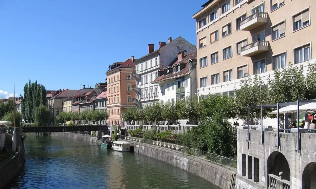 Riverside buildings and a canal under a clear sky in Ljubljana, Slovenia.