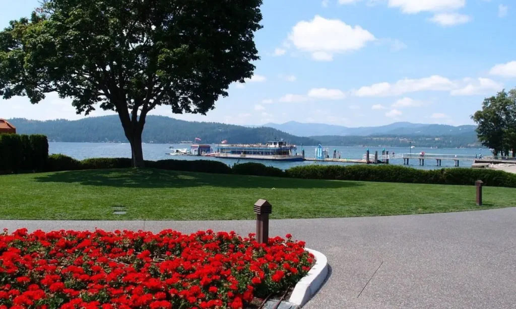 A vibrant garden and lakeside view at Coeur d'Alene City Park and Beach with a boat on the water.