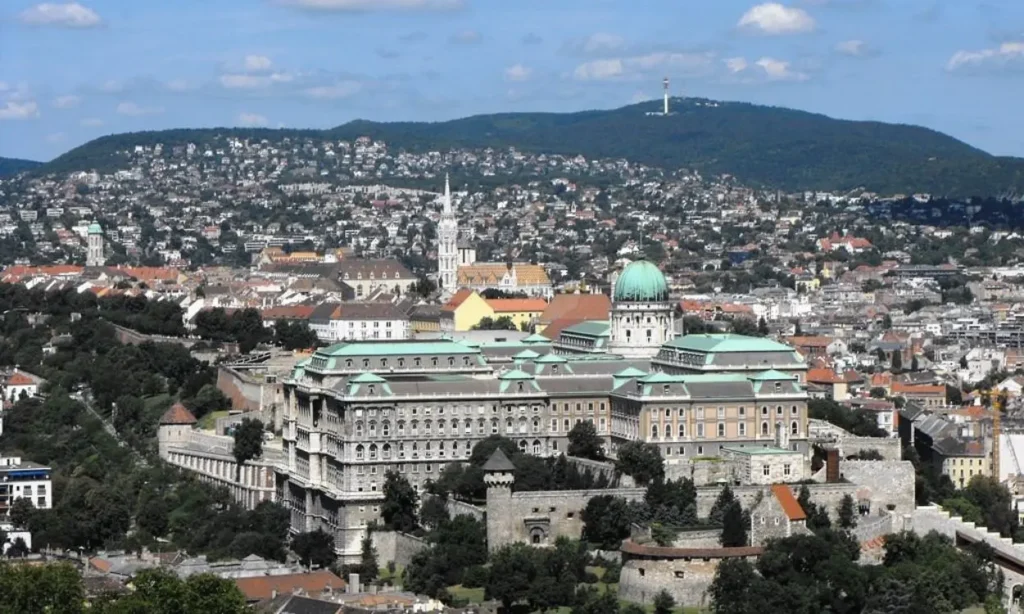 A panoramic view of Hungary with a large domed palace and surrounding hills.