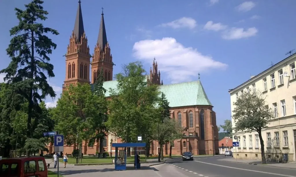 A red brick cathedral with tall spires in Poland on a sunny day.