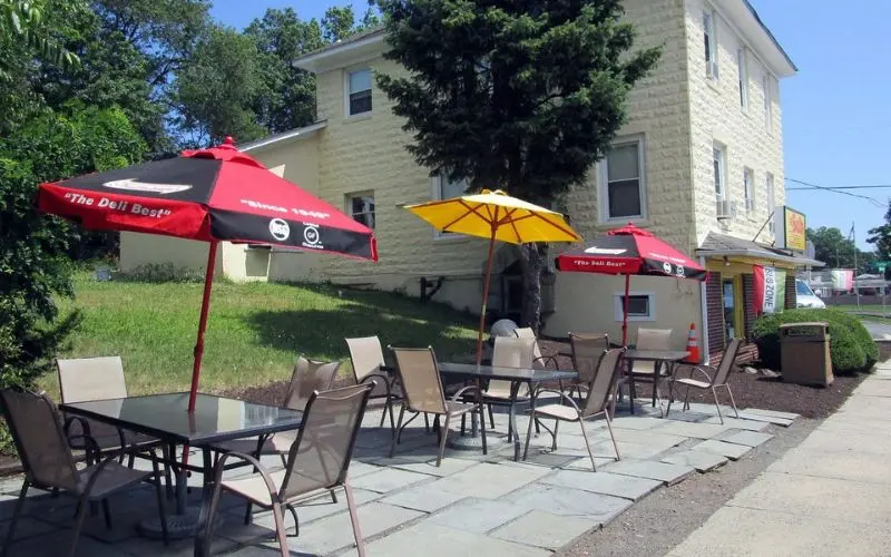 Outdoor tables with umbrellas in front of a deli in Berkeley Heights.