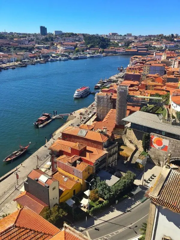 A riverside view of Porto, Portugal with boats and red-roofed buildings.