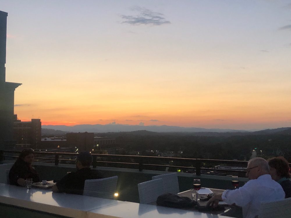 People enjoy drinks at Capella on 9 rooftop while watching a mountain sunset.