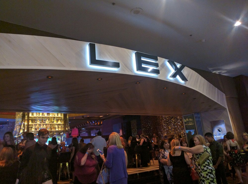 Guests mingle at the stylish entrance of LEX Nightclub, illuminated by its bold, glowing sign.