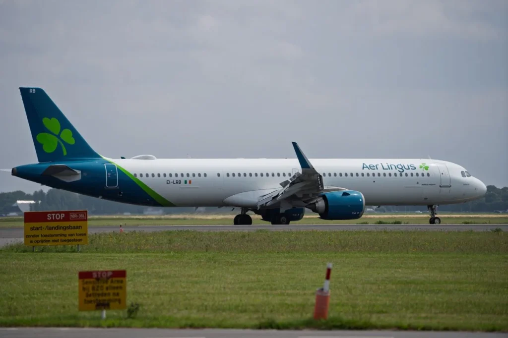 An Aer Lingus Airbus A321neo aircraft taxiing past runway signs on a grass-lined airfield