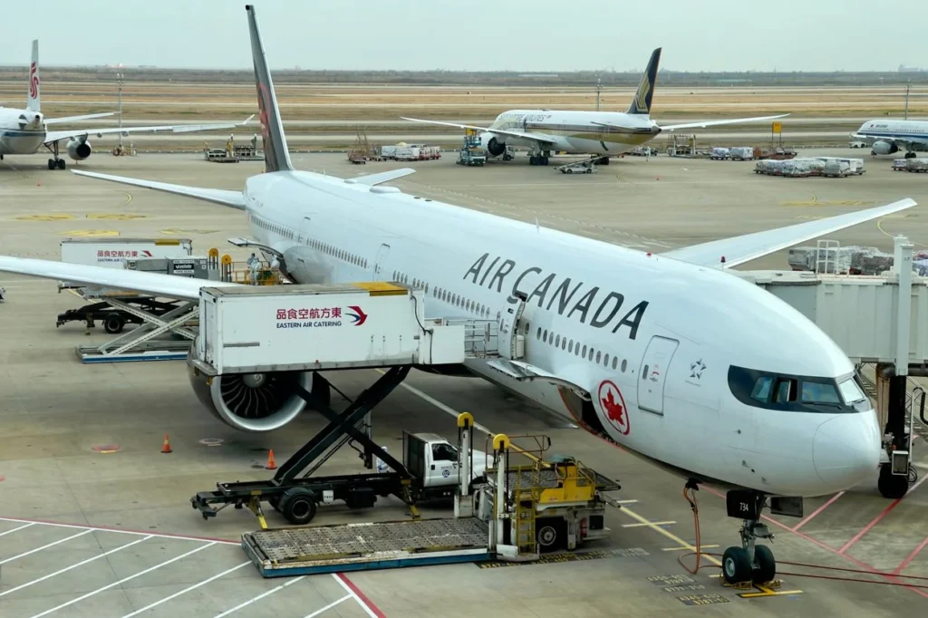 An Air Canada Boeing 777 parked at an airport gate with catering trucks attached