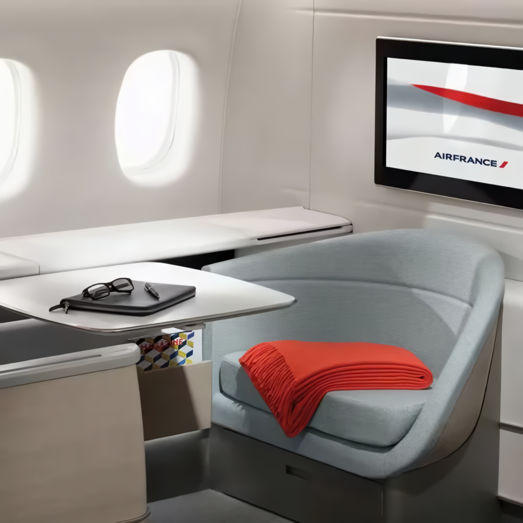 Air France La Première suite seat with a red blanket and an entertainment screen