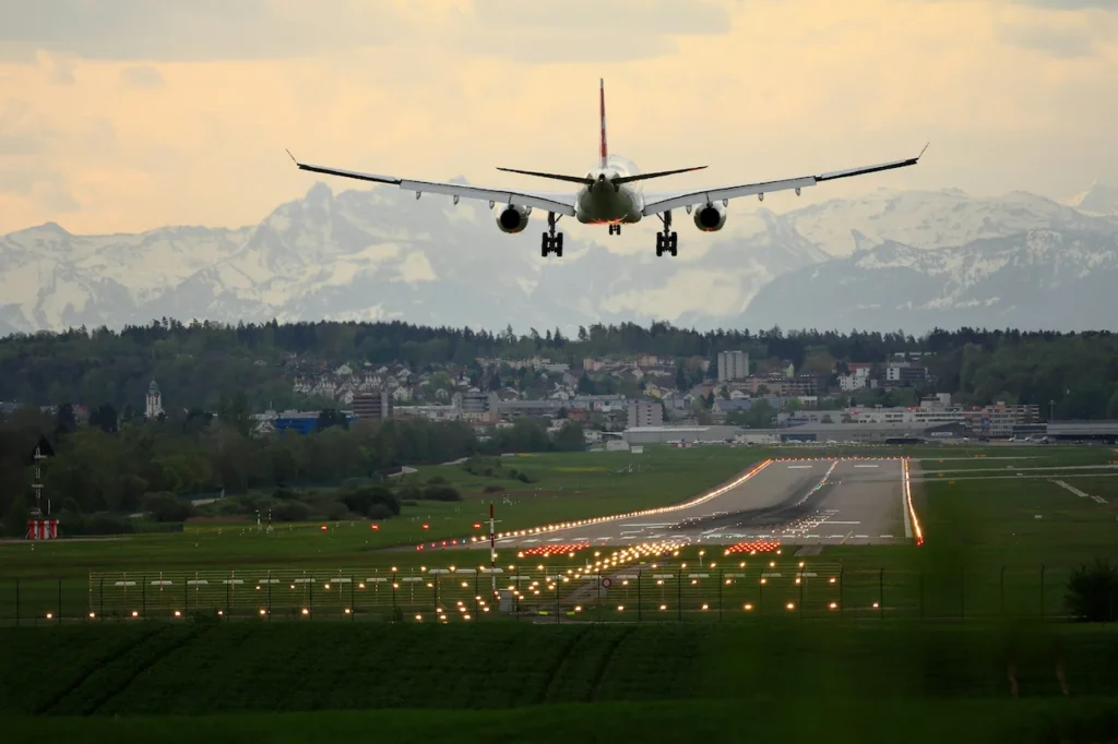 An airplane landing on a runway with snow-covered mountains in the background