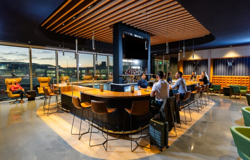 Sleek central bar with leather stools inside Alaska Airlines airport lounge