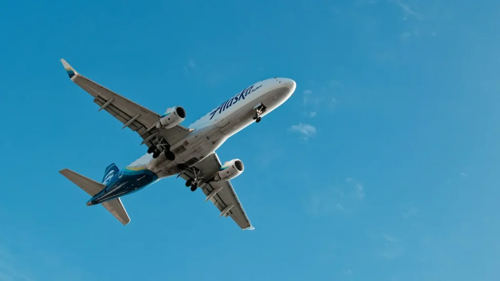 Alaska Airlines SkyWest Embraer 175 jet flying in a bright blue sky