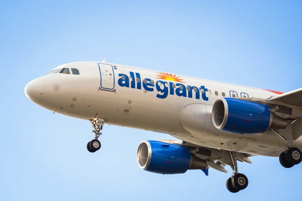 Close-up of an Allegiant Air Airbus A320 aircraft descending with its landing gear down against a blue sky