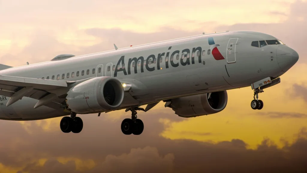 An American Airlines Boeing 737 MAX 8 passenger jet landing against a vibrant sunset sky
