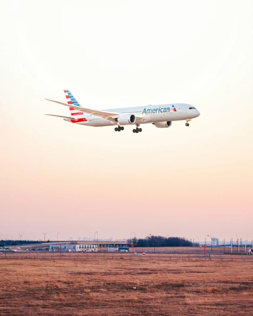 American Airlines Boeing 787 Dreamliner aircraft descending over an open airfield at sunset