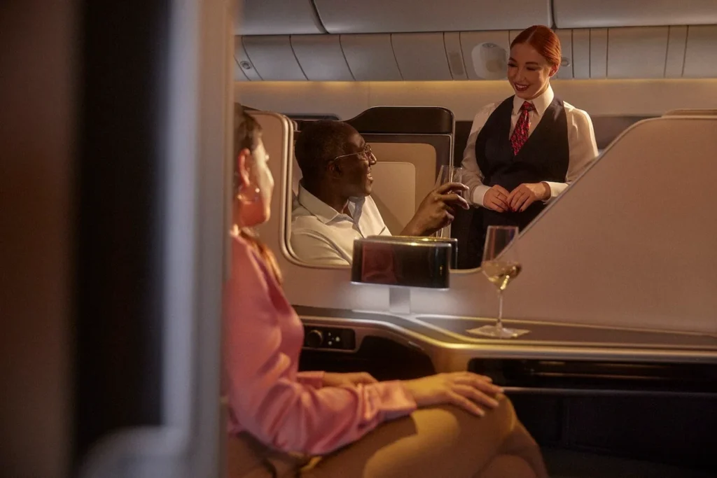 British Airways flight attendant serving passengers in first-class cabin