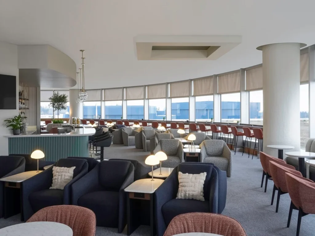 British Airways lounge interior with plush armchairs and windows overlooking airport tarmac