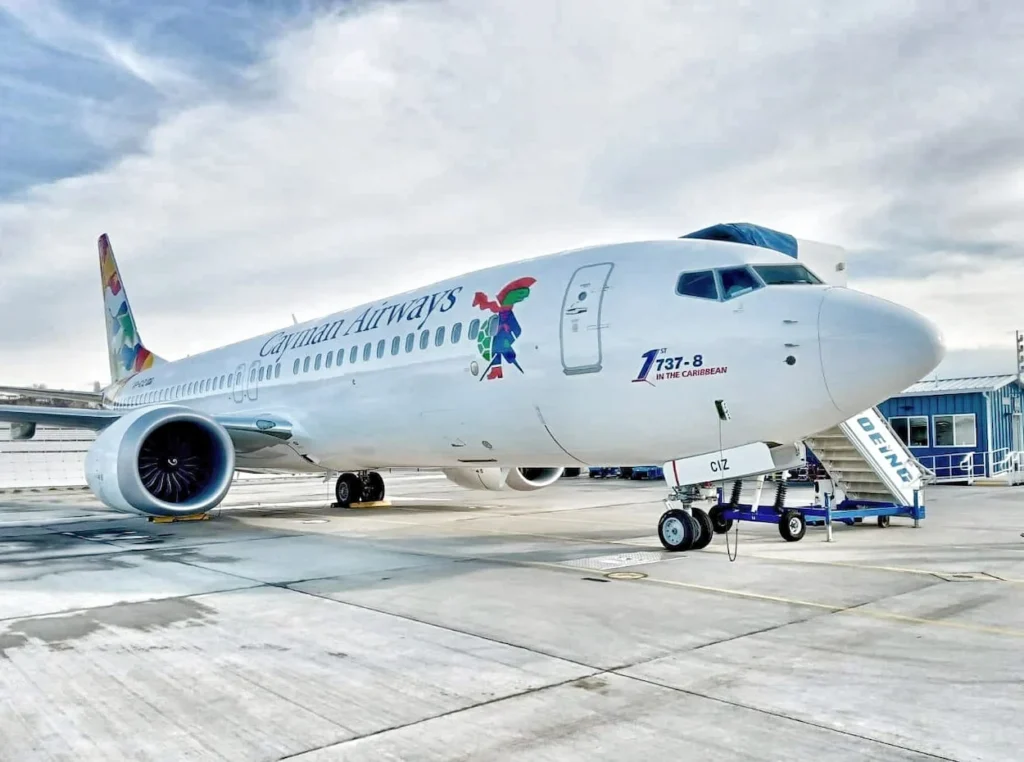 Cayman Airways Boeing 737-8 MAX aircraft parked on the tarmac with boarding stairs attached