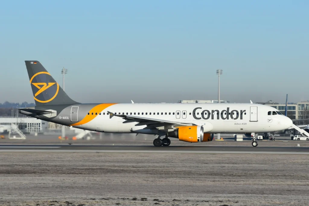 A Condor Airlines Airbus A320 aircraft taxiing on the airport runway under a clear blue sky