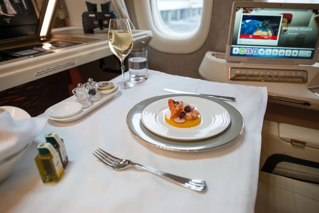 Gourmet seafood appetizer and white wine served on a crisp white tablecloth inside an airplane cabin