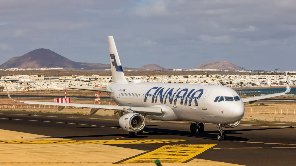 Finnair Airbus A321 narrowbody passenger plane taxiing on a runway with volcanic mountains in the background