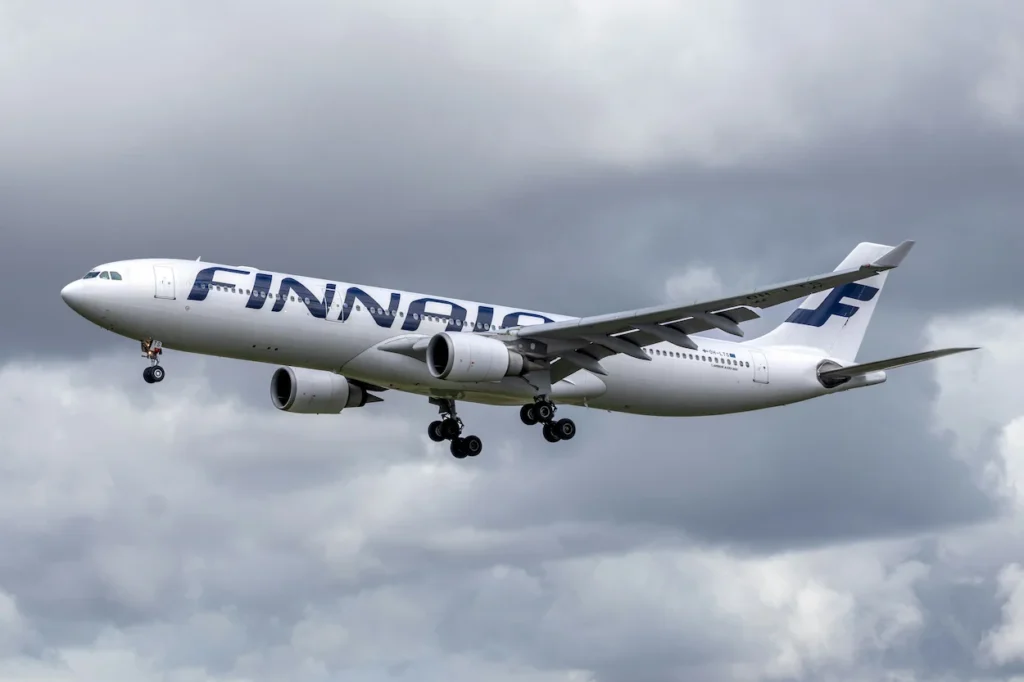 Finnair Airbus A330 descending to land with gear down against overcast clouds