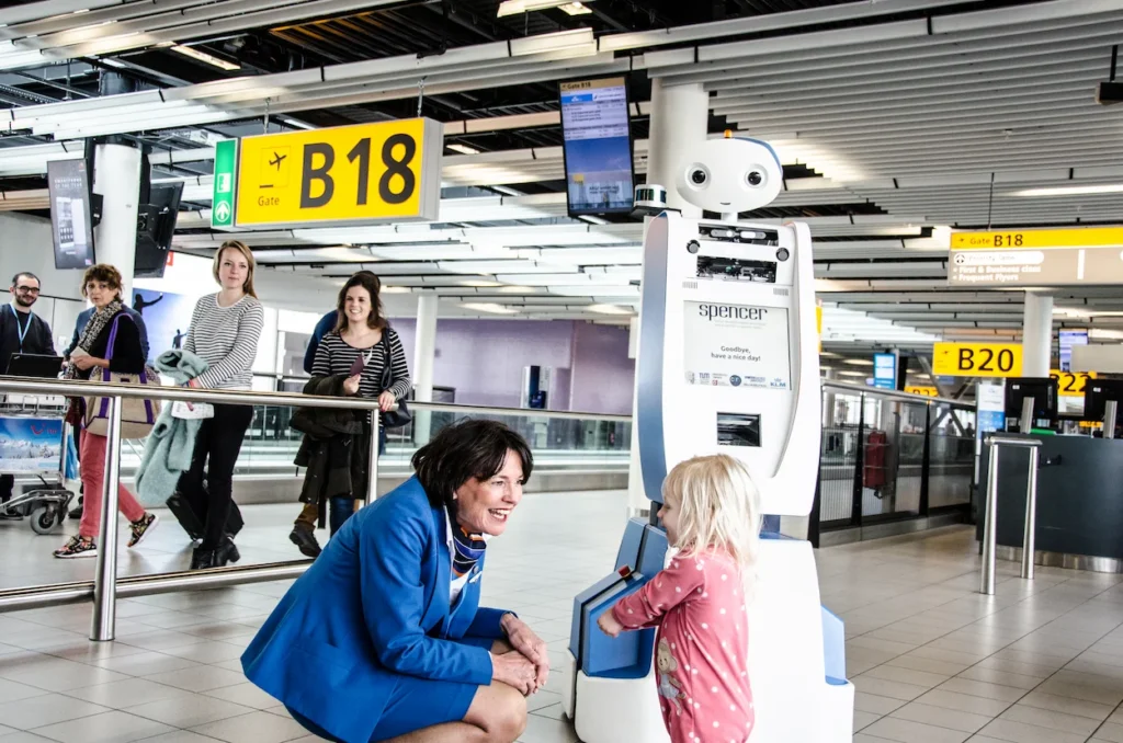 KLM agent with a toddler beside the Spencer robot at Gate B18