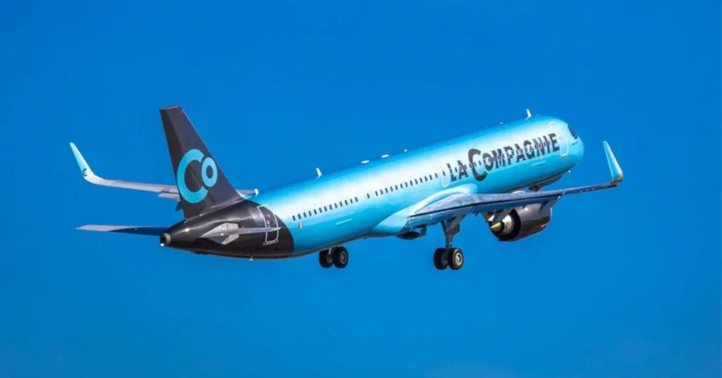 An all-blue La Compagnie Airbus A321neo passenger airplane climbing into a clear blue sky