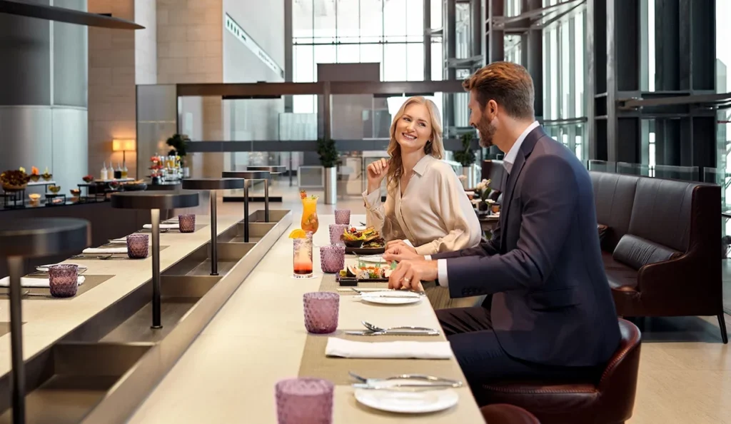 A couple dining at the sleek bar counter inside Qatar Airways' Al Safwa First Lounge