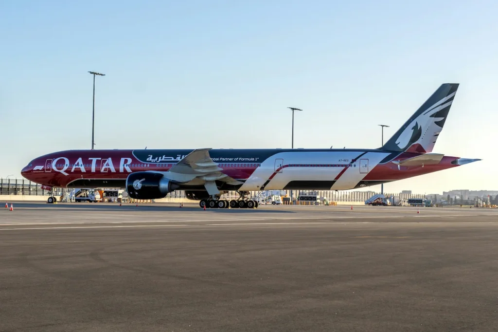 A side view of a Qatar Airways Boeing 777 in a special Formula 1 livery parked on the airport tarmac