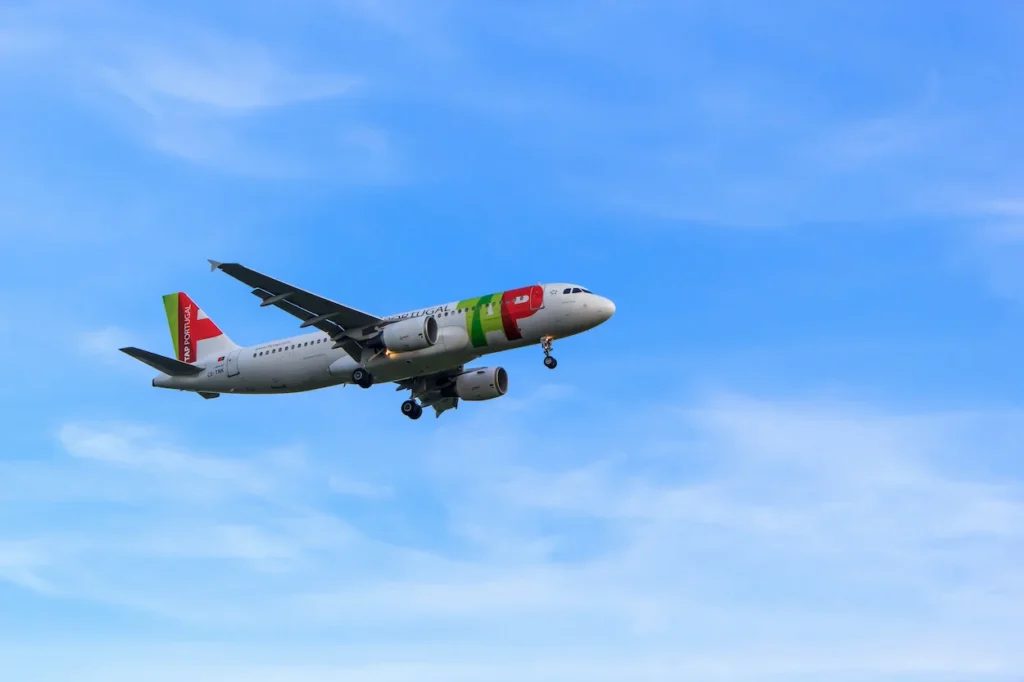 A TAP Air Portugal Airbus passenger airplane flying low with its landing gear deployed