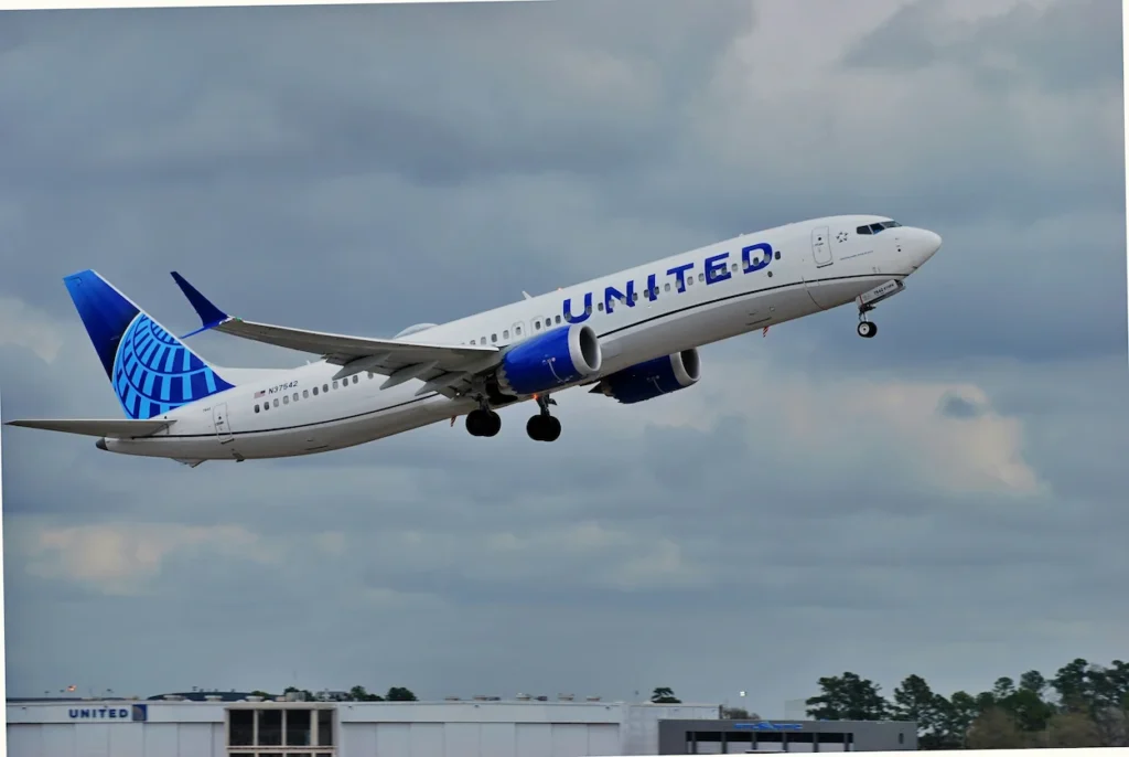 A white United Airlines Boeing 737-800 passenger airplane climbing into a cloudy blue sky after takeoff
