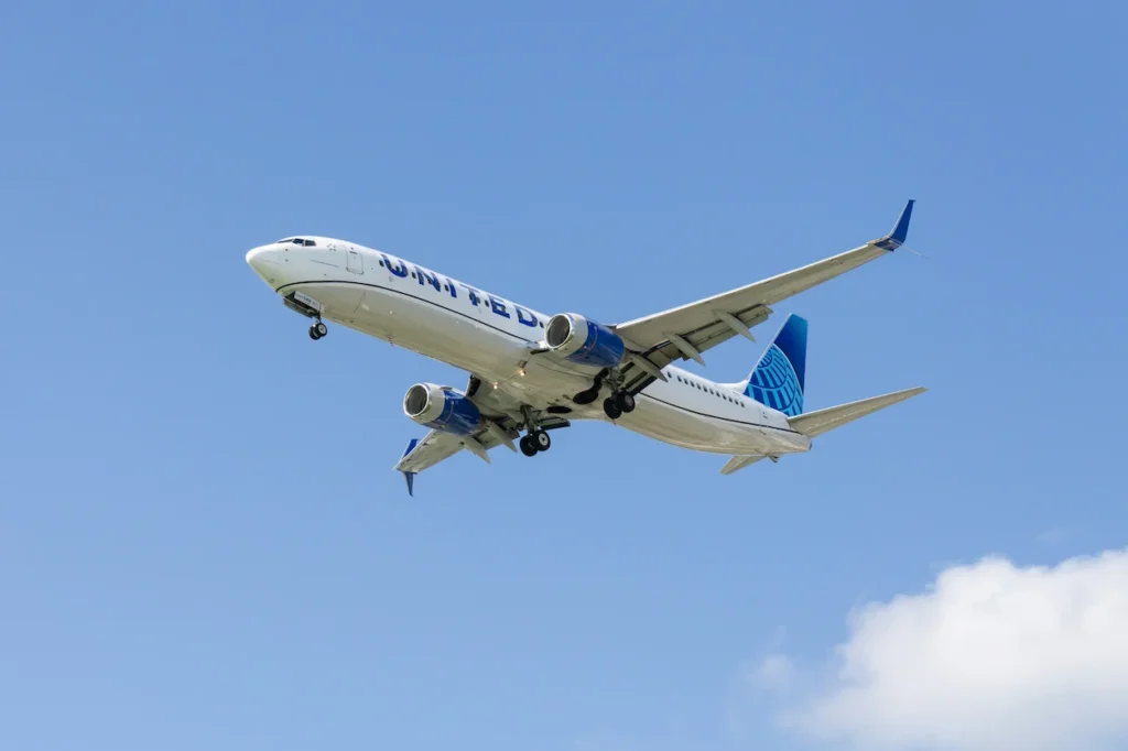 United Airlines Boeing 737 passenger airplane descending through a blue sky on landing approach