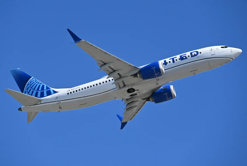 United Airlines Boeing 737 MAX passenger jet climbing steeply into a clear blue sky