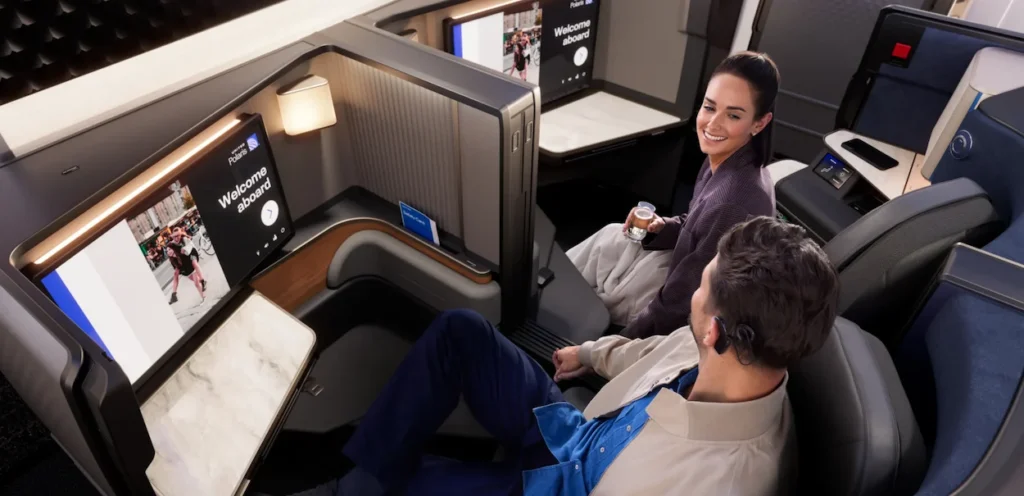Two passengers relax and converse in a modern United Polaris business class suite cabin