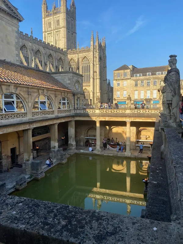 Ancient Roman Baths in Bath with green pool and stone columns.