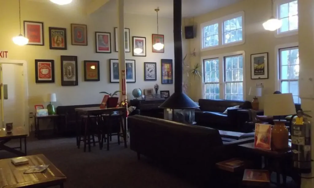 Cozy common room with couches, a hanging fireplace, and framed art on the walls.