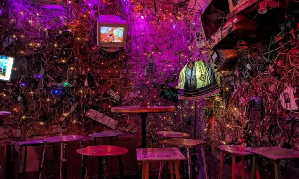 A colorful, eclectic bar interior filled with wires and glowing lights at Szimpla Kert.