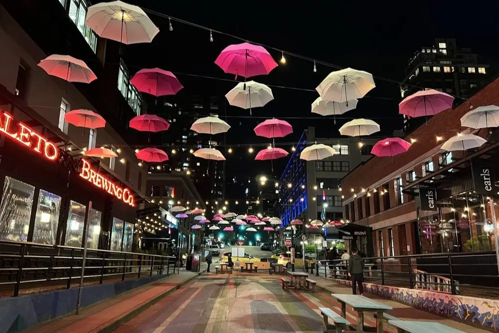 Hanging umbrellas and neon signs outside Yaletown Brewing Company at night.