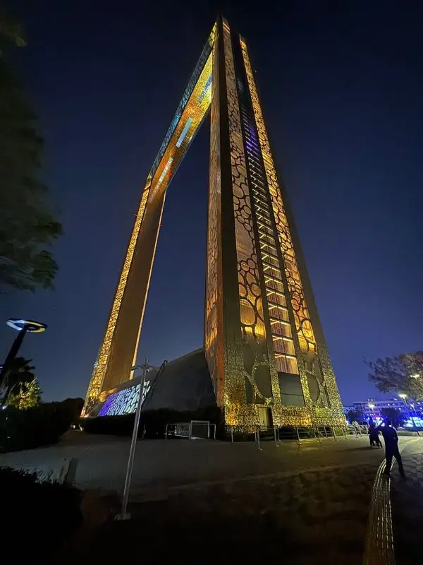 The illuminated Dubai Frame tower at night viewed from below.
