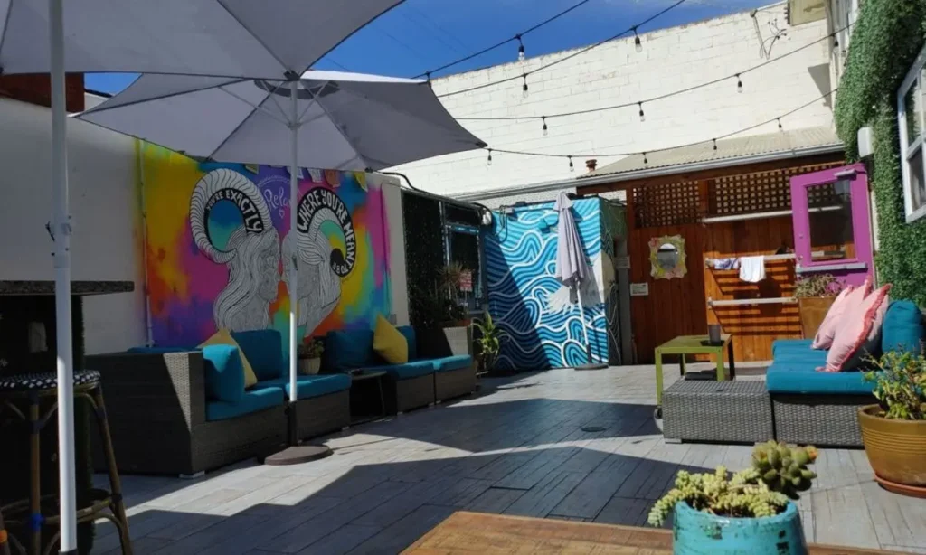 Bright outdoor lounge with colorful murals, patio seating, and umbrellas.