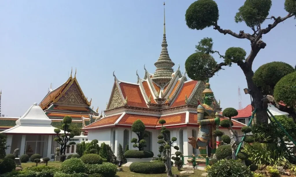 Ornate temple buildings with decorative rooftops and gardens in Bangkok, Thailand.